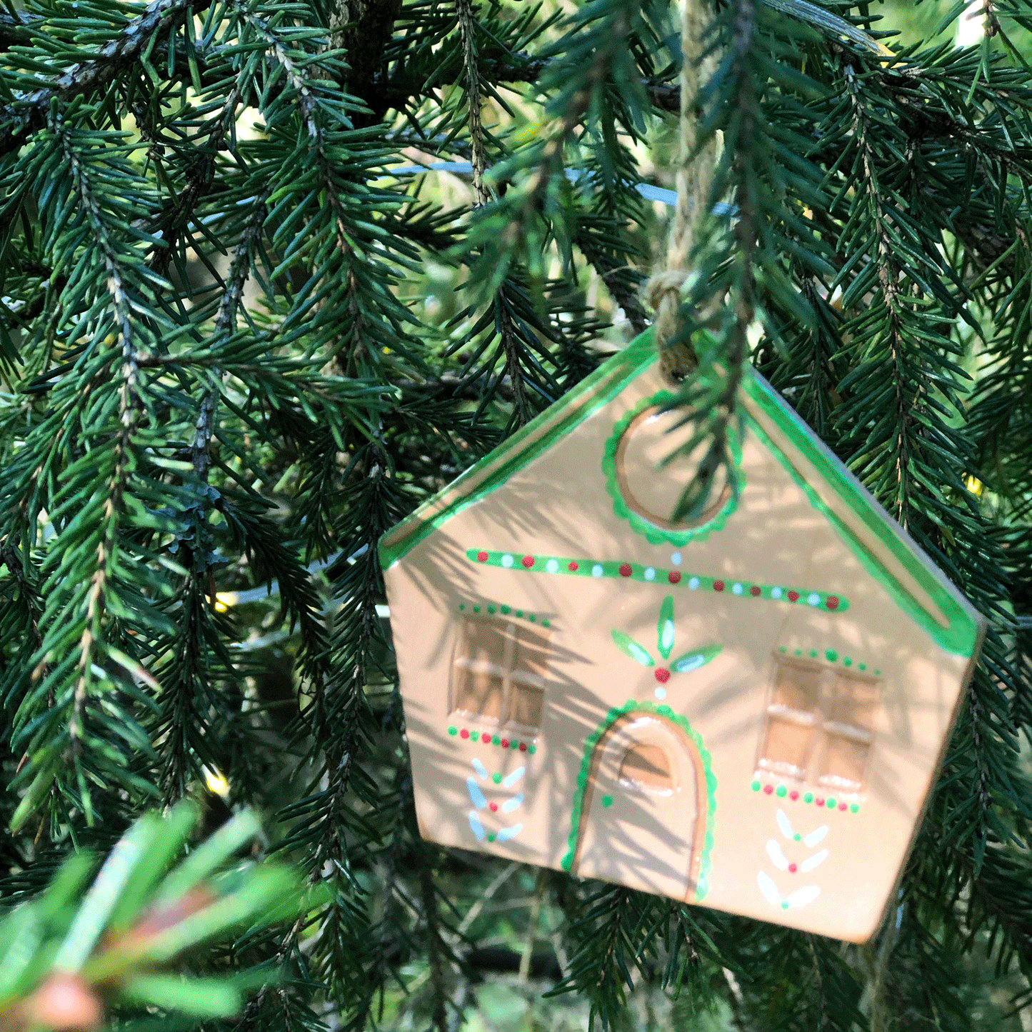 A gingerbread house decoration hanging in a Christmas tree