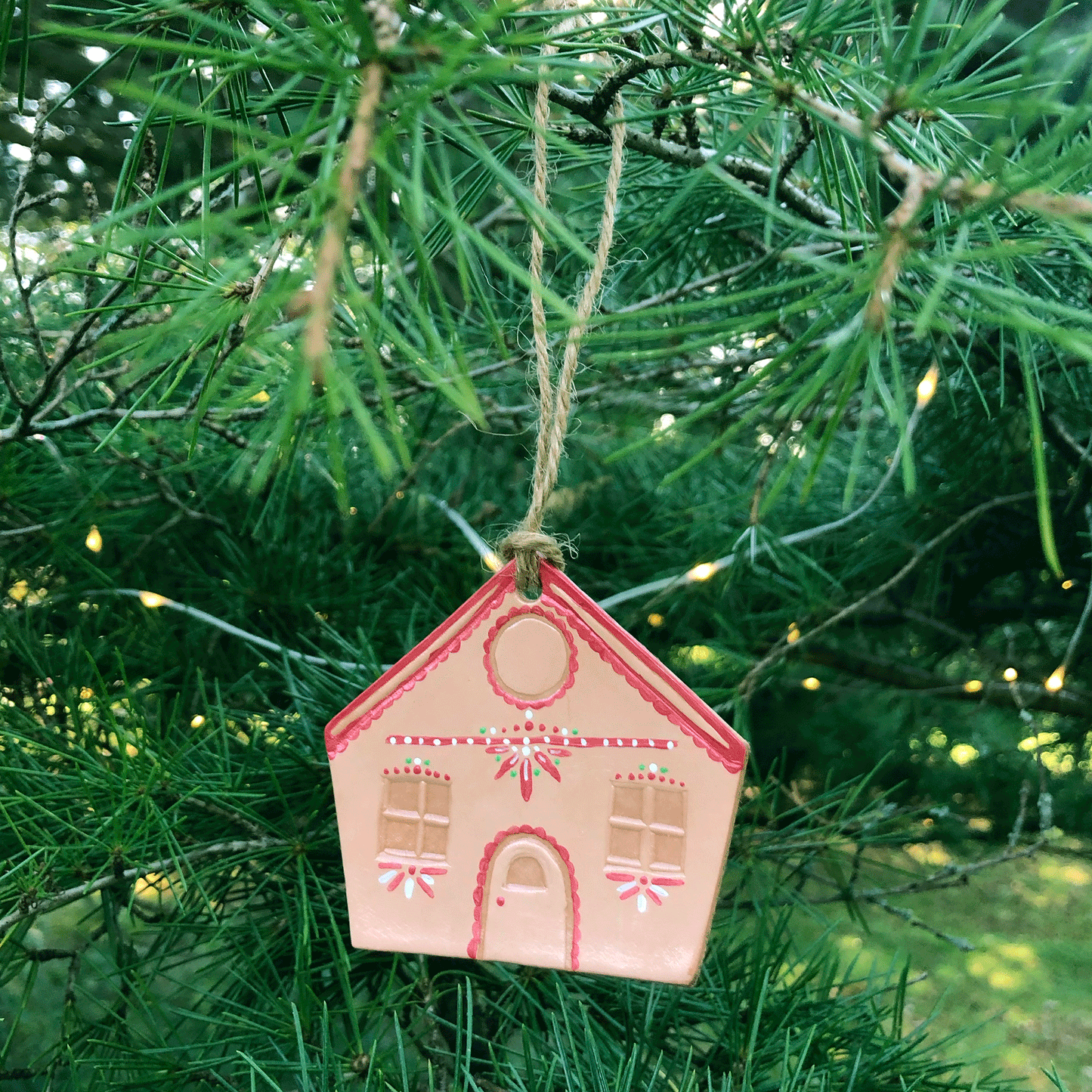 A red painted leather gingerbread house decoration hanging in a tree