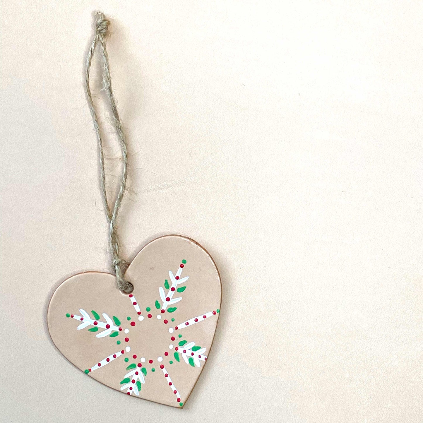 a heart decoration painted with a festive snowflake pattern sits on a neutral background