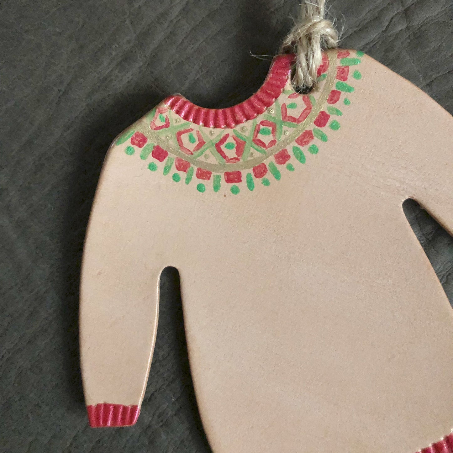 Close up of a festive jumper ornament which has been painted with a red geometric pattern