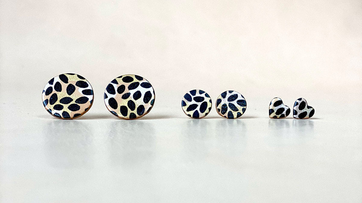 A row of 3 pairs of studs in different sizes. Each has been painted with an animal print design