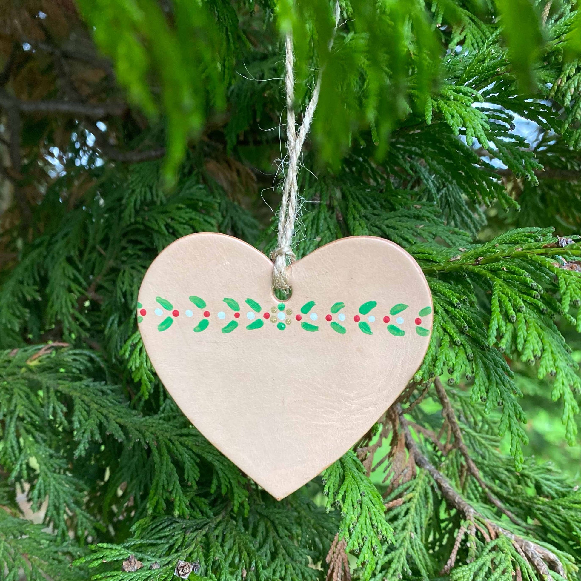 A painted heart Christmas decoration hangs in a tree