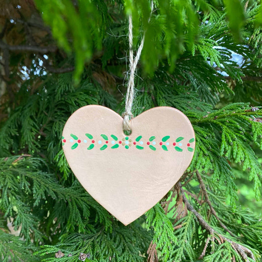 A painted heart Christmas decoration hangs in a tree