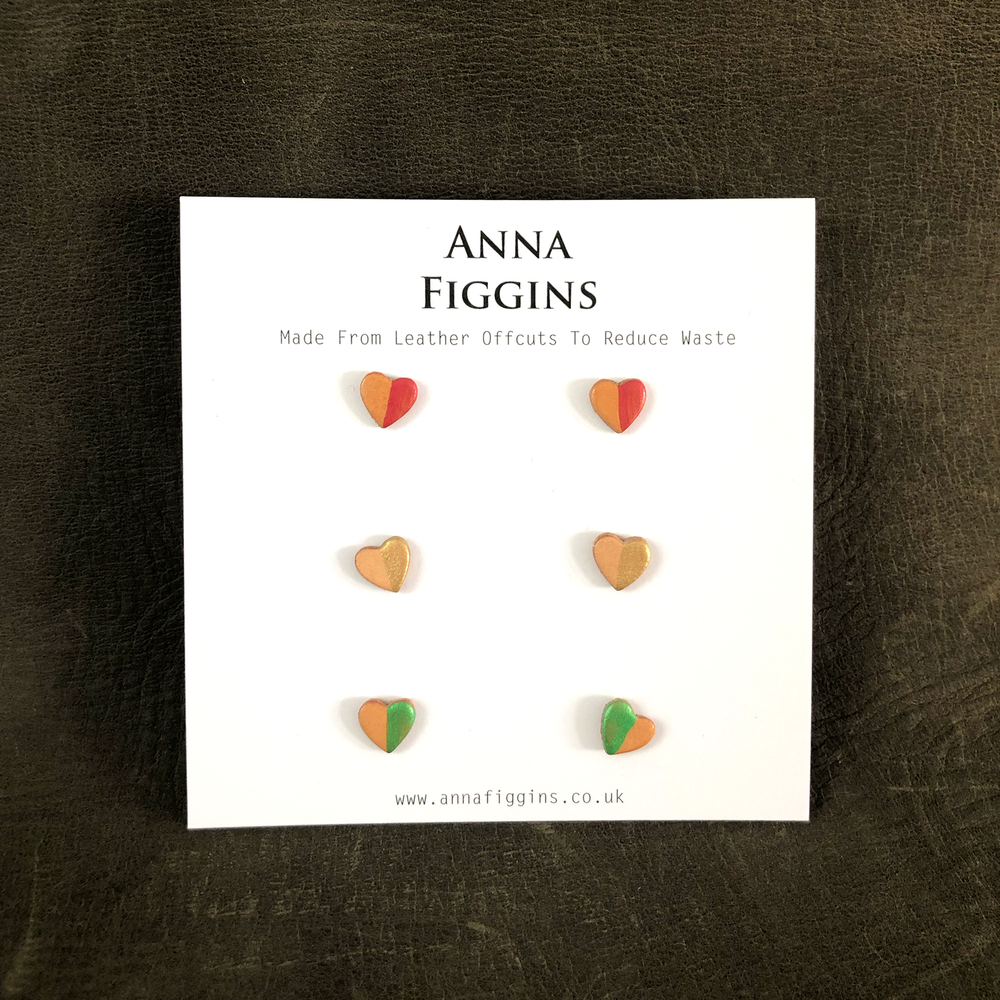 Three pairs of heart shaped stud earrings on their display card. Half of each pair has been painted - one with red, one with green and another with gold paint