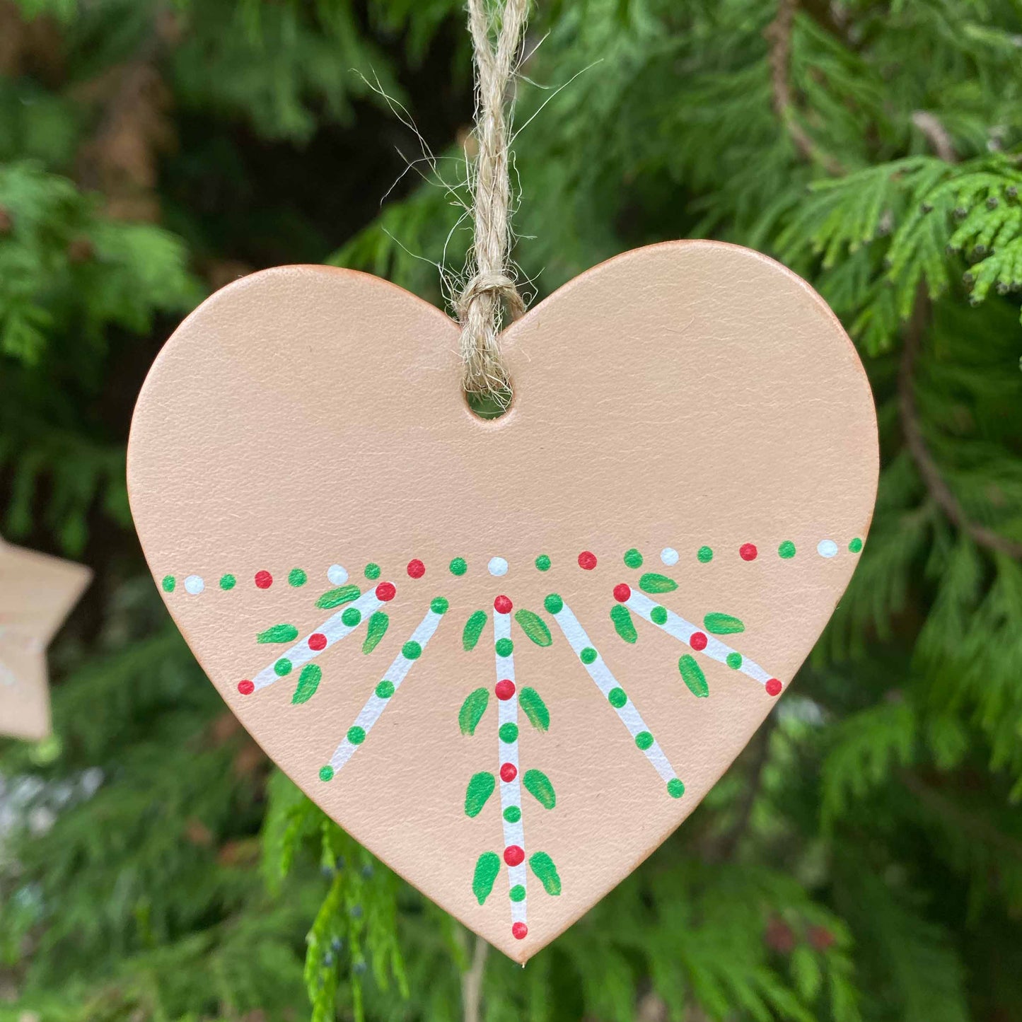 A heart decoration painted with a folk pattern hangs in a Christmas tree