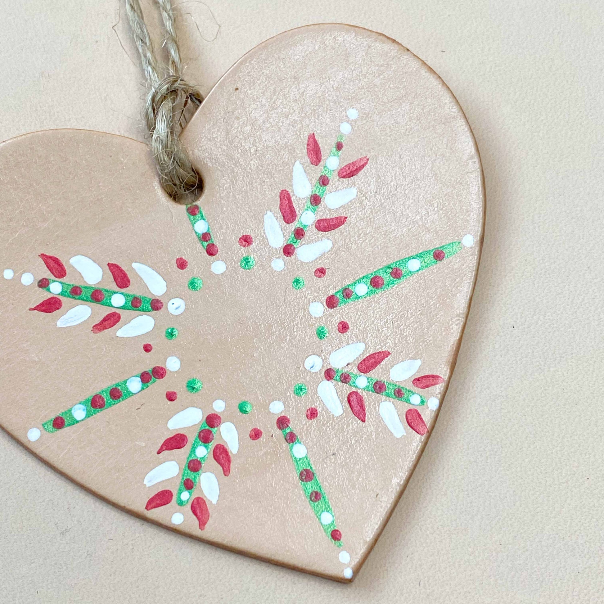 Close up of a heart shaped Christmas ornament painted with a snowflake design