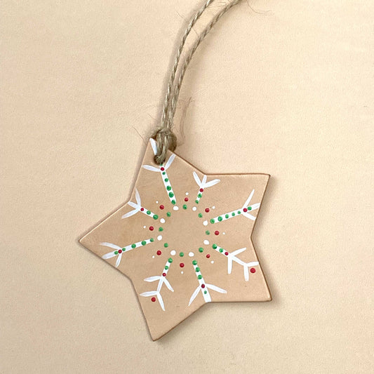 Star-shaped leather ornament with snowflake design on a beige background