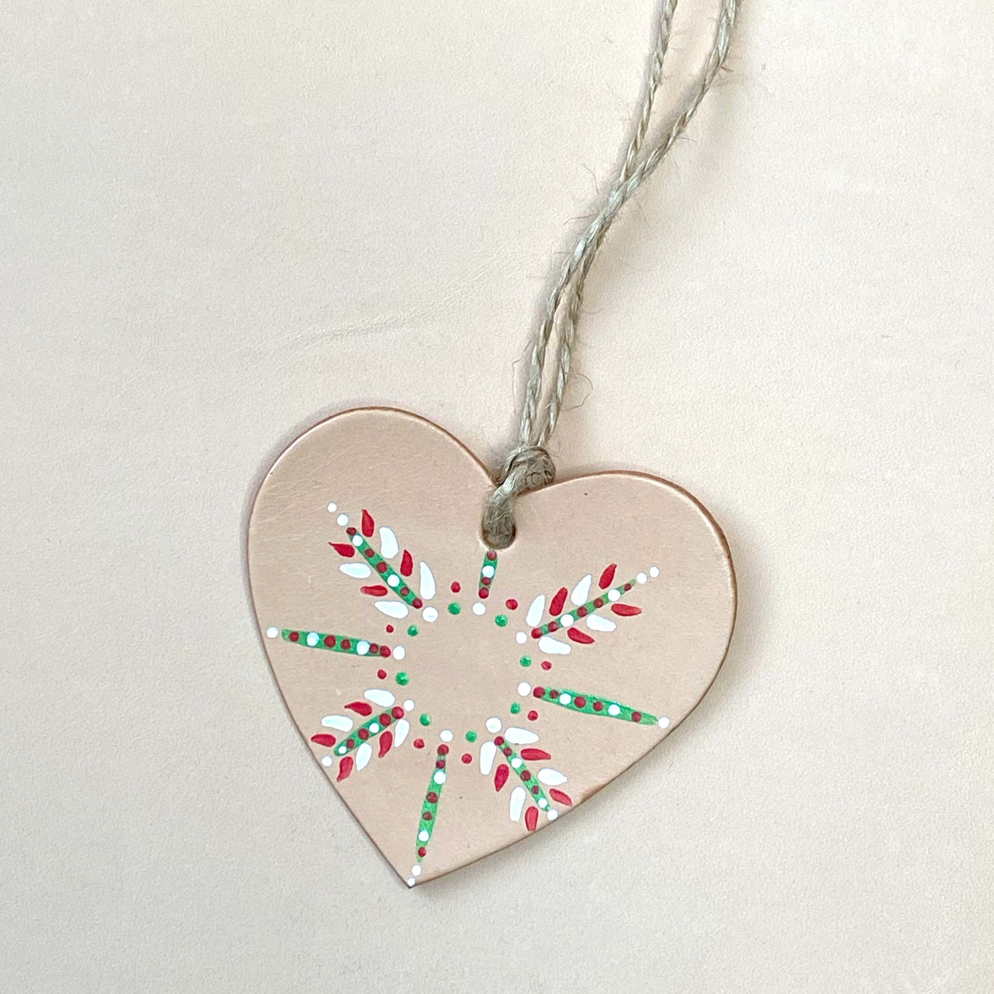 A colourful snowflake patterned heart shaped Christmas decoration on a neutral background