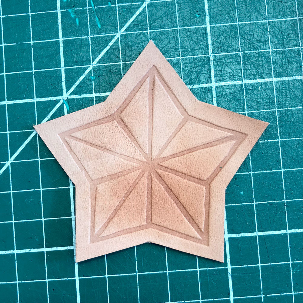 A STAR SHAPED PIECE OF LEATHER WITH AN EMBOSSED GEOMETRIC STAR PATTERN