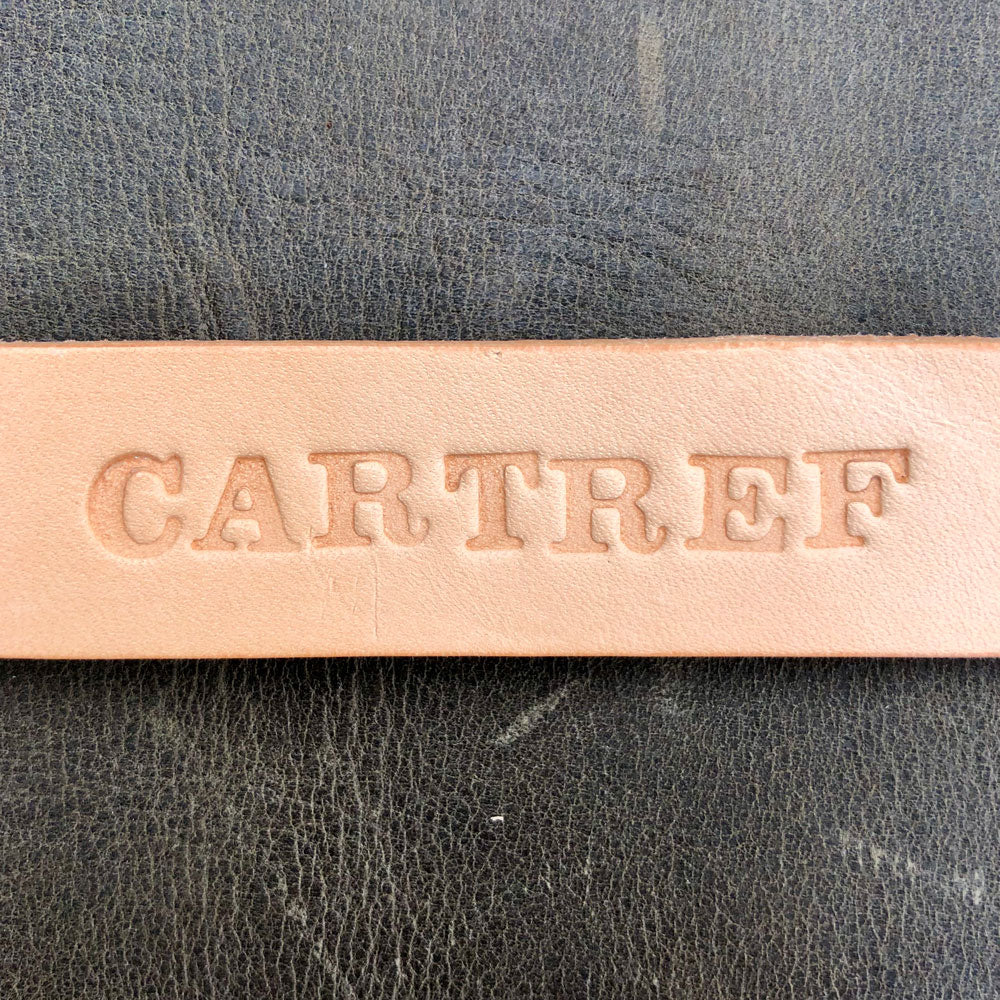 Close up image of the word "CARTREF" stamped into natural coloured leather