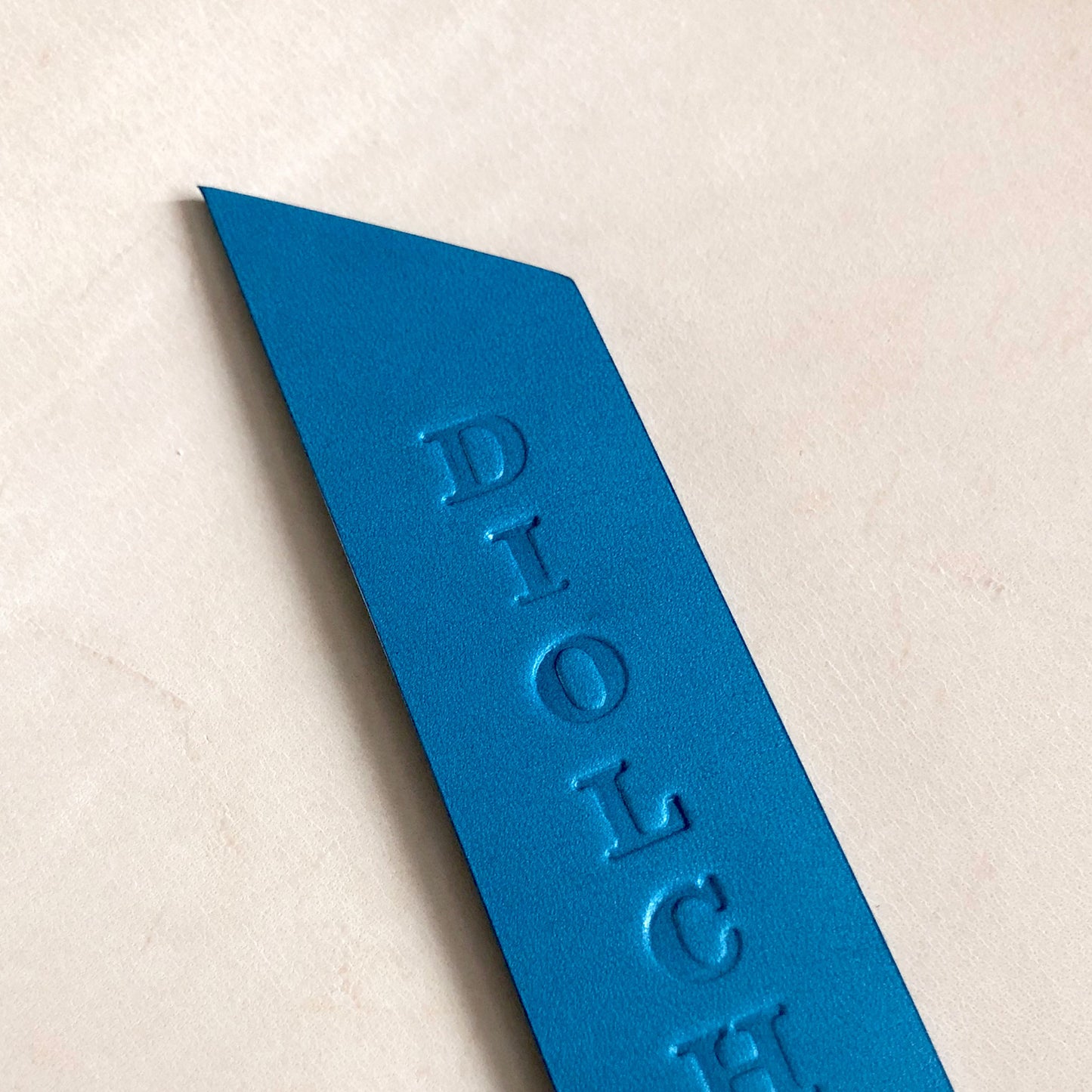Handmade leather bookmark stamped with "DIOLCH"